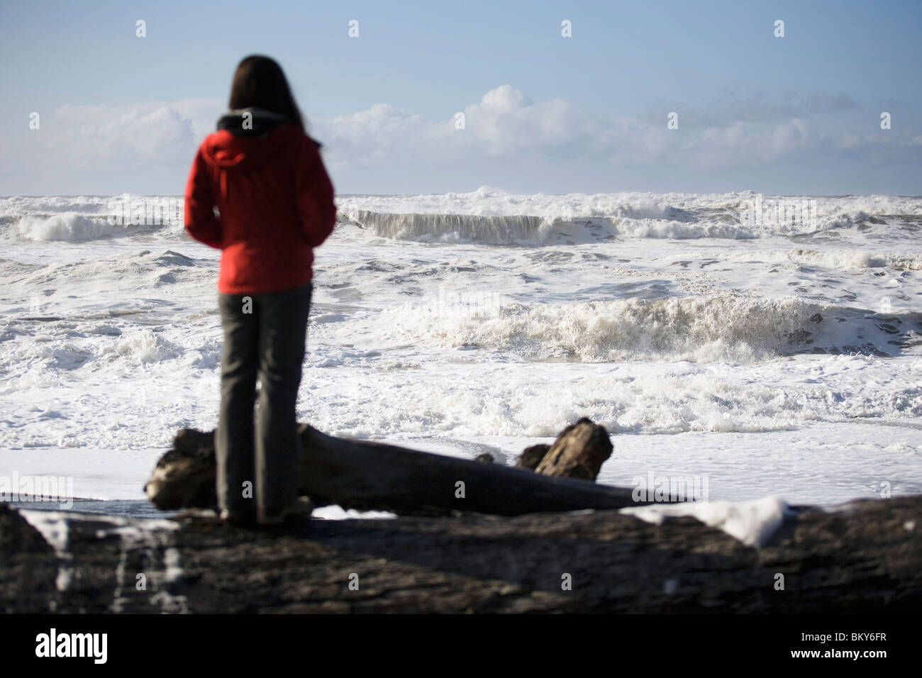 Una donna guarda l'oceano onde di un mare turbolento. Foto Stock
