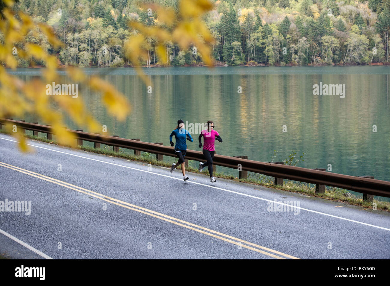 Due giovani donne correre in stride su una caduta di giorno in Lago Crescent nel Parco Nazionale di Olympic. Foto Stock
