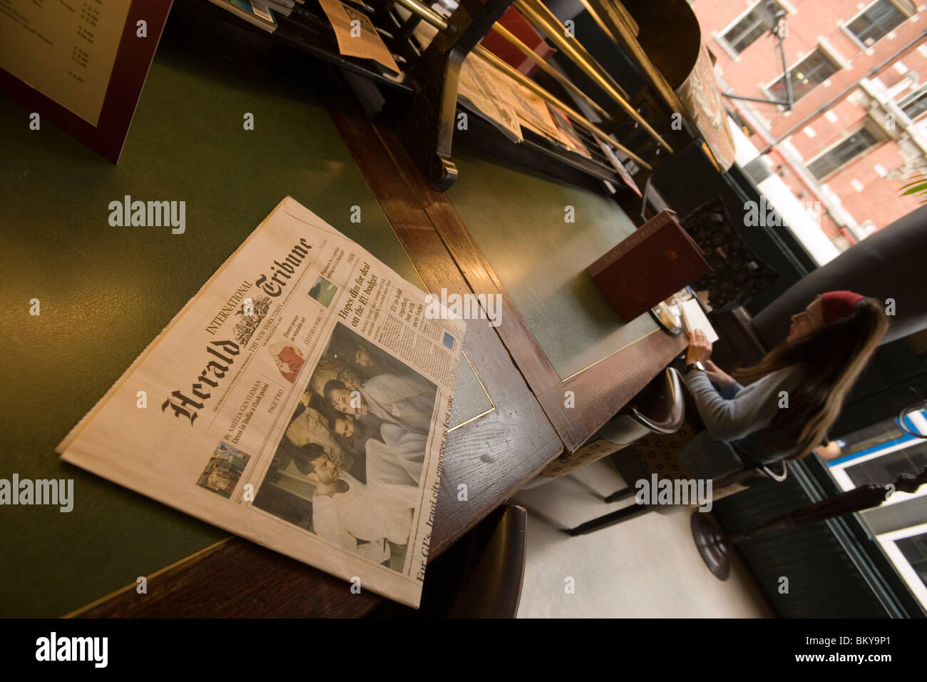 Giornale, Donna, Cafe Americain, Leidseplein, giovane donna seduta al Cafe Americain, lettura e mangiare, giornale giacente sulla scheda Foto Stock