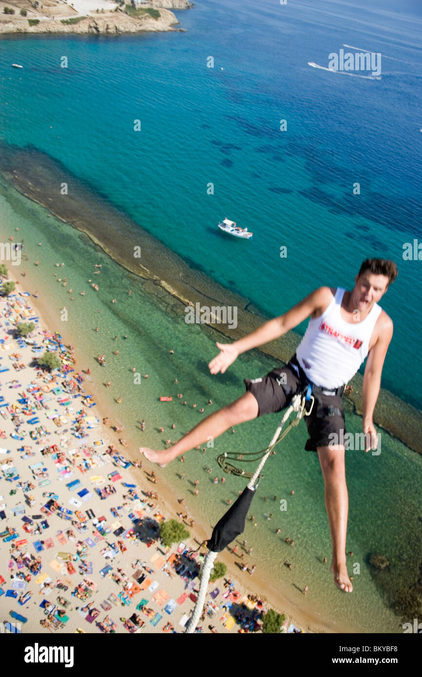 Giovane uomo bungee jumping su Paradise Beach, Mykonos, Grecia Foto Stock