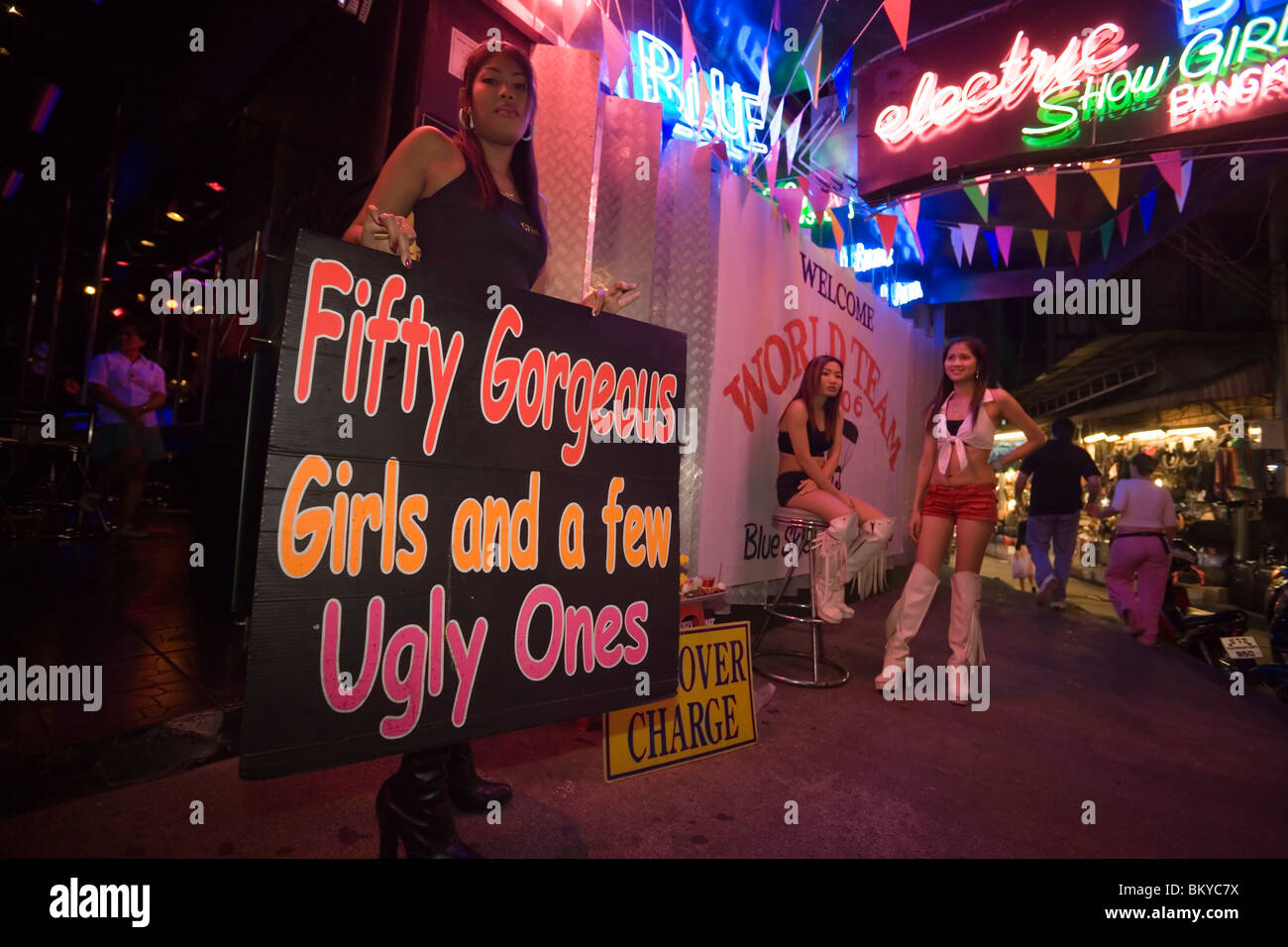 Tre go-go le ragazze nella parte anteriore di un nightclub, una donna tenendo un cartello, Patpong, la luce rossa e il quartiere dei divertimenti, Bang Rak dis Foto Stock