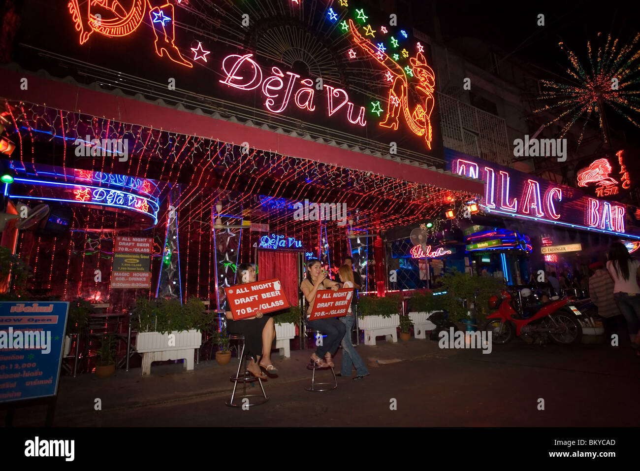 La donna seduta di fronte a go-go bar 'DeJa Vu' e che presentano segni, Soi Cowboy, un quartiere a luci rosse, Th Sukhumvit Bangkok, Tha Foto Stock