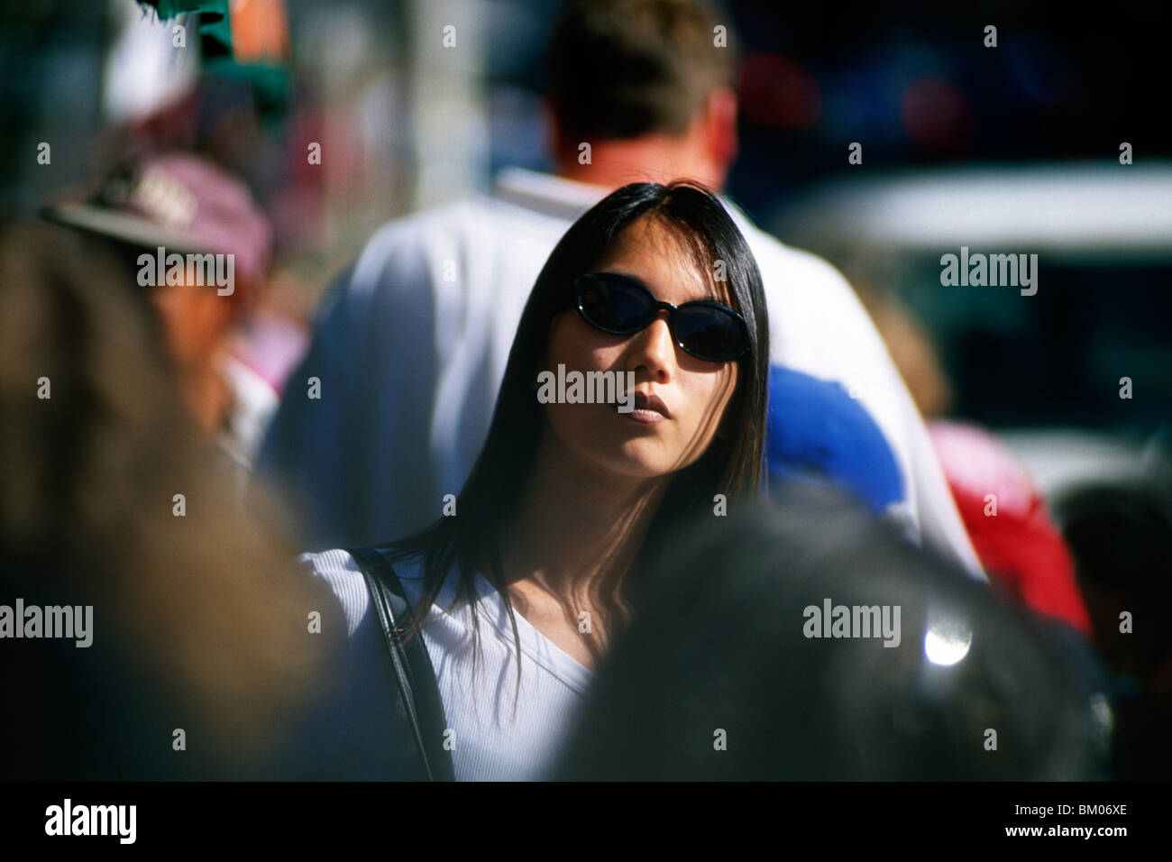 Asian giovane donna che indossa gli occhiali da sole nella folla Foto Stock