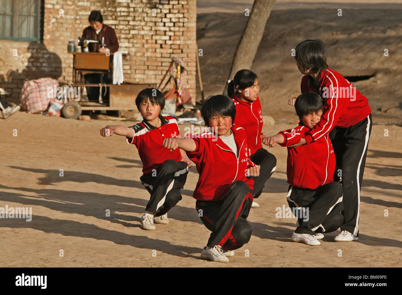 La mattina presto il Kung Fu di formazione, la scuola nei pressi di Shaolin, una donna che lavora su una macchina da cucire in background, Song Shan, Henan provi Foto Stock