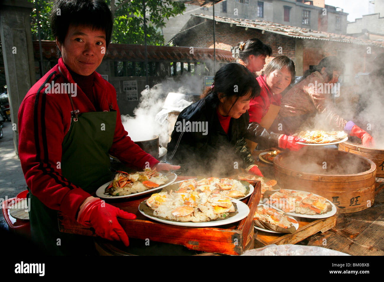 Cameriera con piastre di cottura a vapore degli alimenti di mare, cottura a vapore in bambù cestelli, cucina Cinese, Jinfeng, Changle, provincia del Fujian, Cina Foto Stock