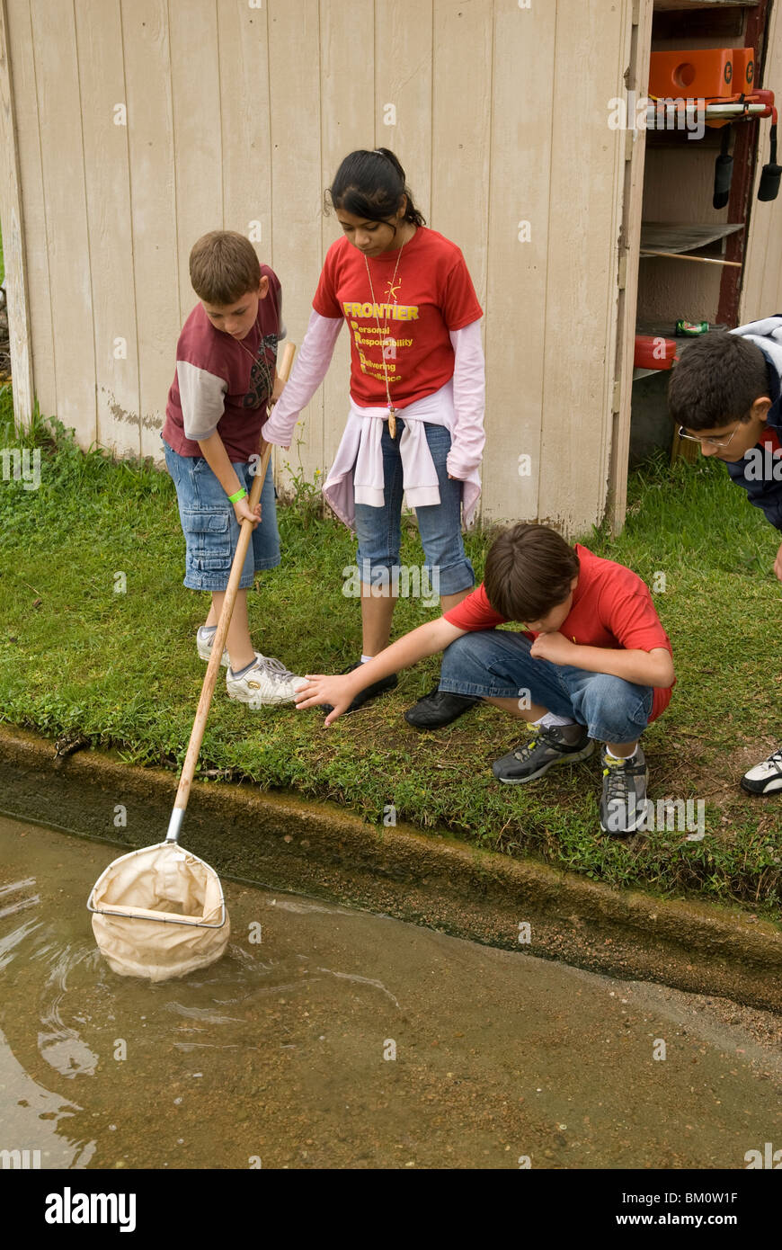 Gli studenti delle scuole medie ispaniche usano la rete per raccogliere fango dal fondo del lago per studiare la qualità dell'acqua nel centro di apprendimento all'aperto. ©Bob Daemmrich Foto Stock