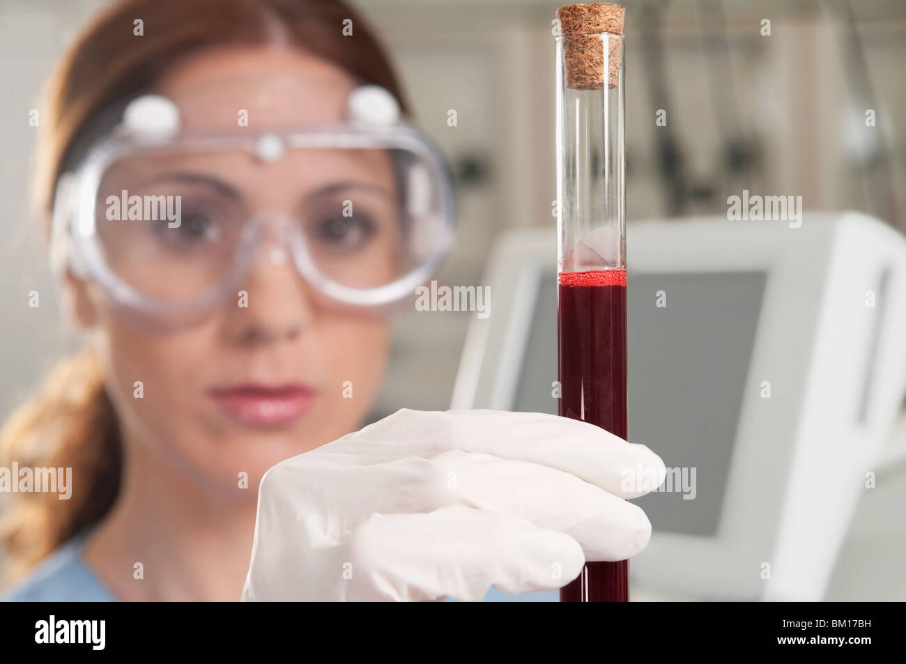 Femmina tecnico di laboratorio di analisi di un campione di sangue in un tubo di prova Foto Stock