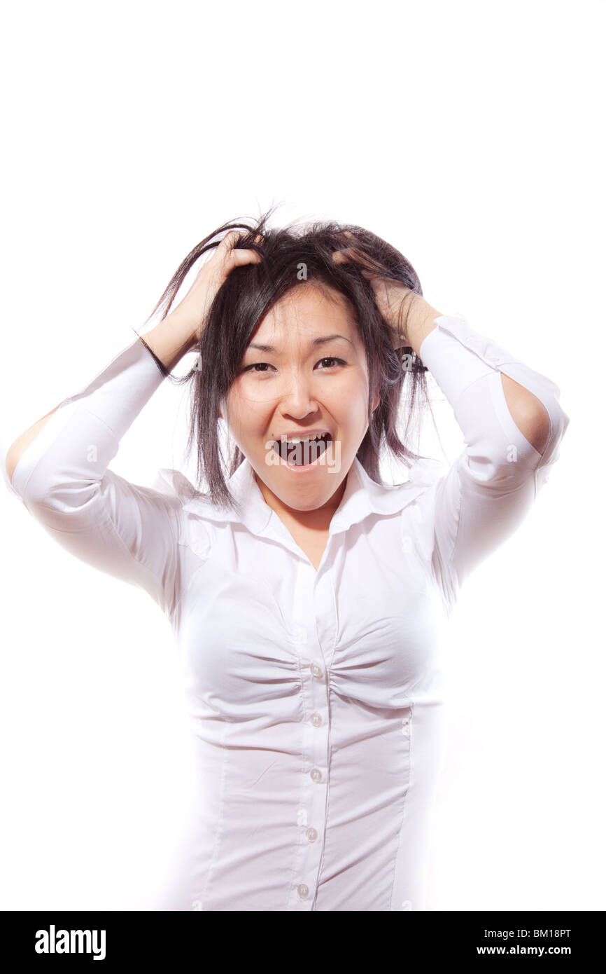 La ragazza attraente in una camicia bianca lacrime su se stesso i capelli con grida Foto Stock