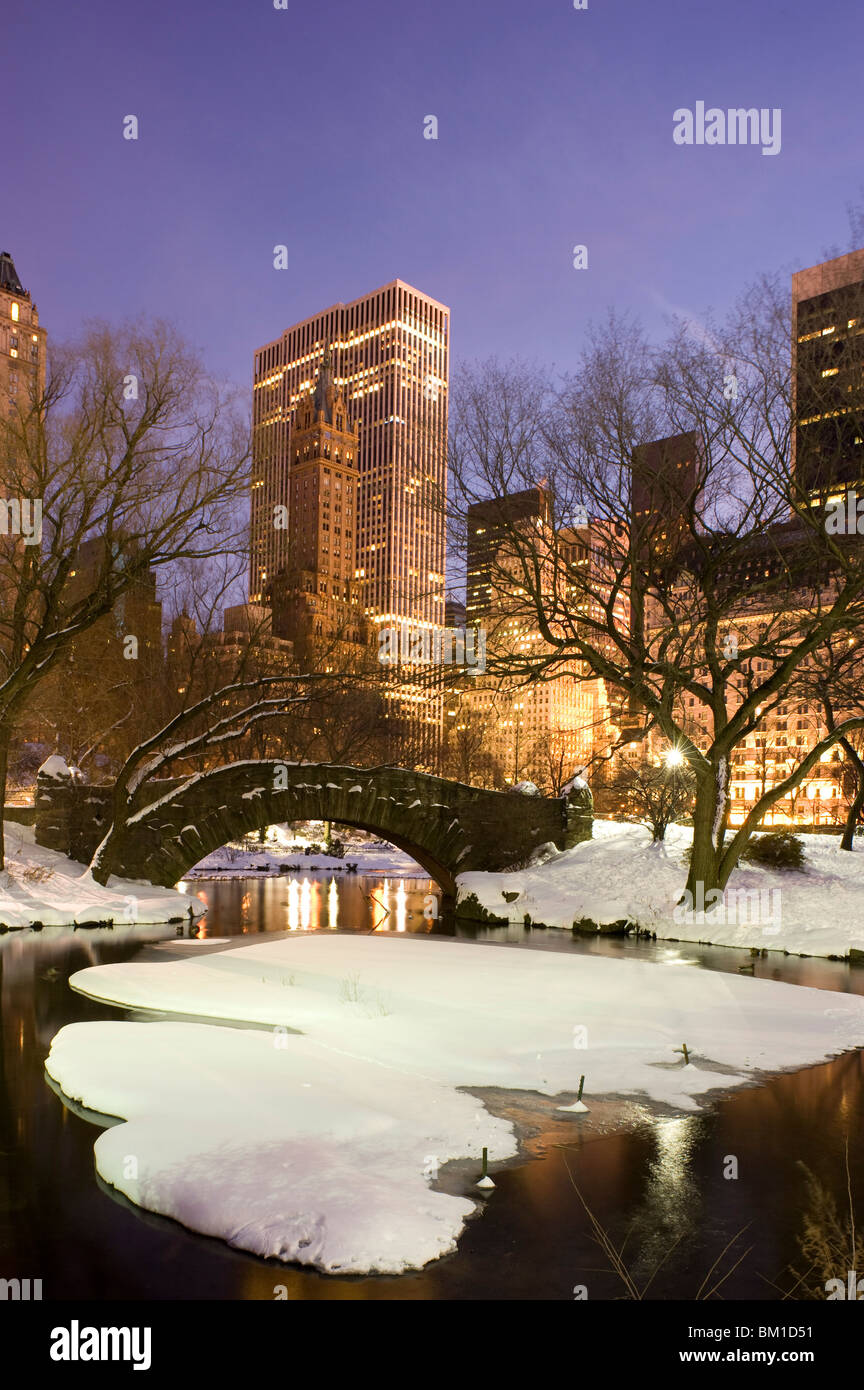 Una vista del Gapstow Bridge di Central Park e dello skyline della città al tramonto dopo una tempesta di neve, la città di New York, nello Stato di New York, Stati Uniti d'America Foto Stock