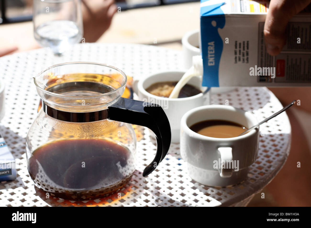 Il caffè e il latte che viene versato in tazze in vacanza a Puerto Pollenca appartamento vicino alla spiaggia. Foto Stock