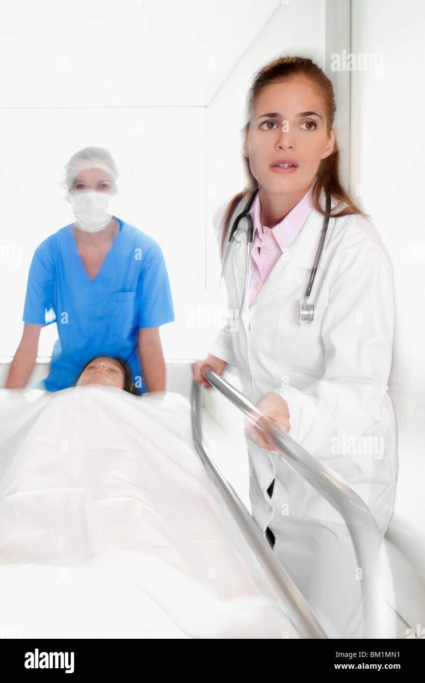 I medici spingendo un paziente su una barella in ospedale in un corridoio di ospedale Foto Stock