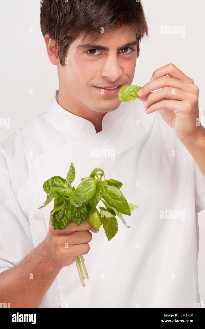 L'Uomo odore di foglie di basilico e sorridente Foto Stock