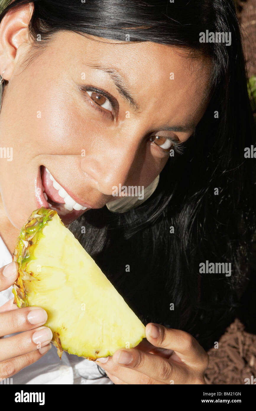 Ritratto di una donna di mangiare una fetta di ananas Foto Stock