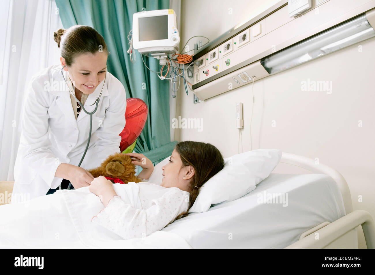 Ragazza sul letto di un ospedale in fase di esame da parte di un medico di sesso femminile Foto Stock