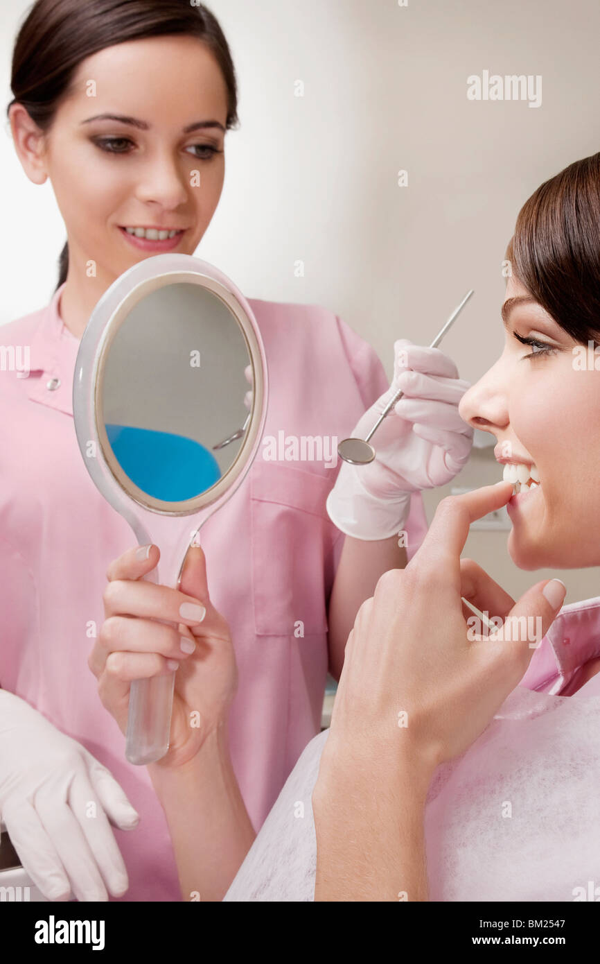 Donna che guarda in uno specchio in studio dentistico Foto Stock