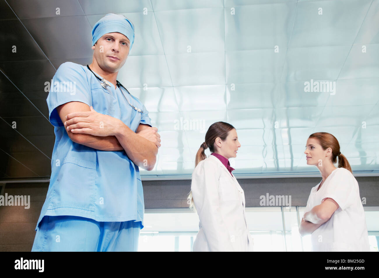 Chirurgo maschio in piedi con i suoi colleghi a discutere in background Foto Stock