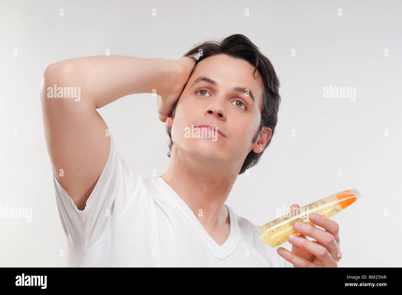 Uomo di applicare gel sui suoi capelli Foto Stock