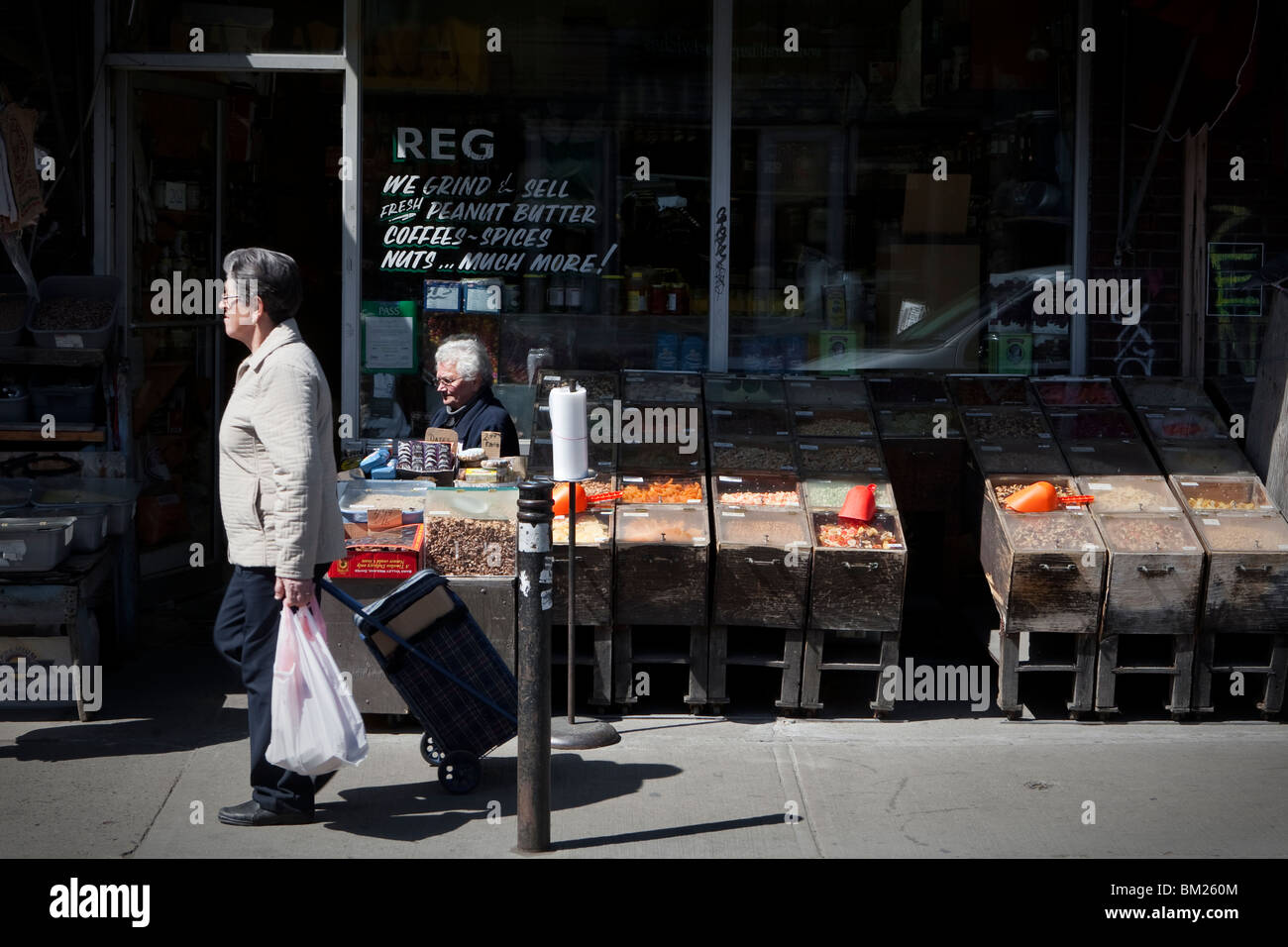 Una donna cammina da una piccola drogheria a Toronto Kensington market Foto Stock