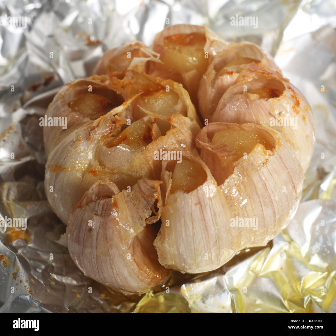 Una testa di lampadina o di appena tostato aglio, ancora sulla carta stagnola veniva cucinato in dopo aver top tritato e olio versato su Foto Stock