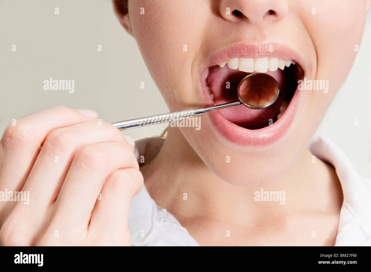 Donna esaminando i suoi denti con specchio angolato Foto Stock