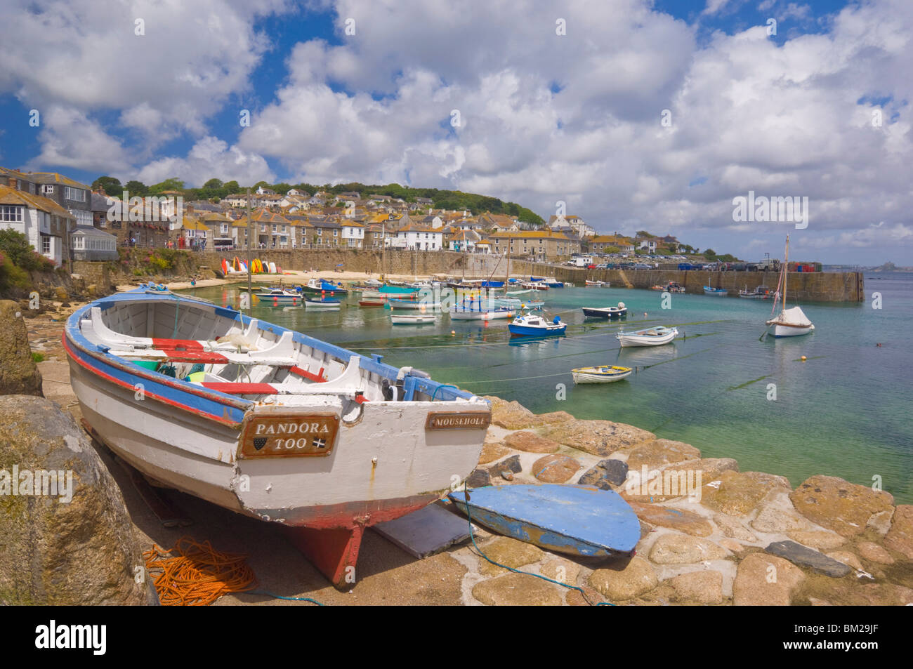 Piccola barca sul molo e piccole barche nel porto racchiuso a Mousehole, Cornwall, Regno Unito Foto Stock