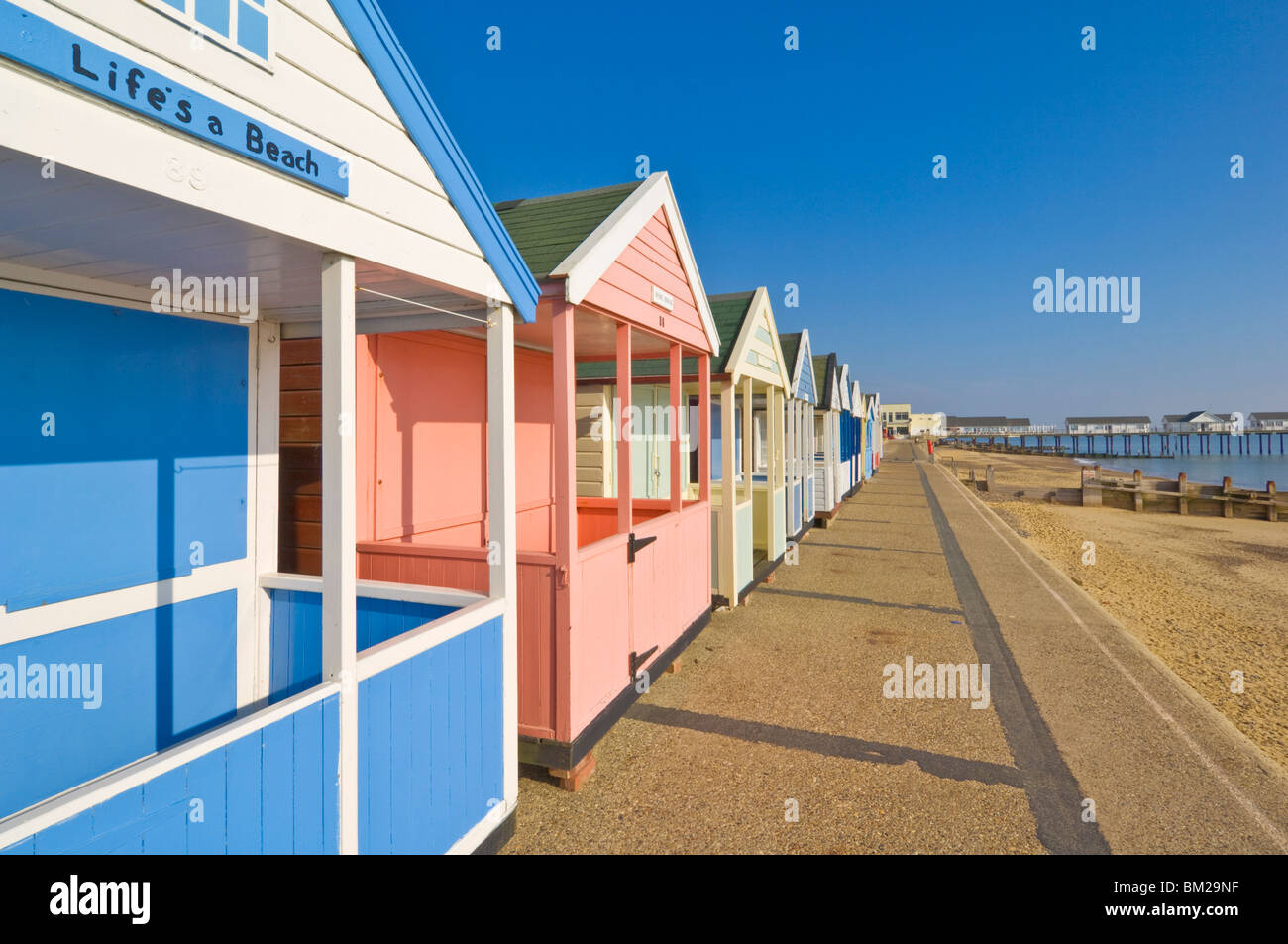 Dipinto luminosamente cabine sulla spiaggia, al pomeriggio di sole, sul lungomare, Southwold, Suffolk, Regno Unito Foto Stock