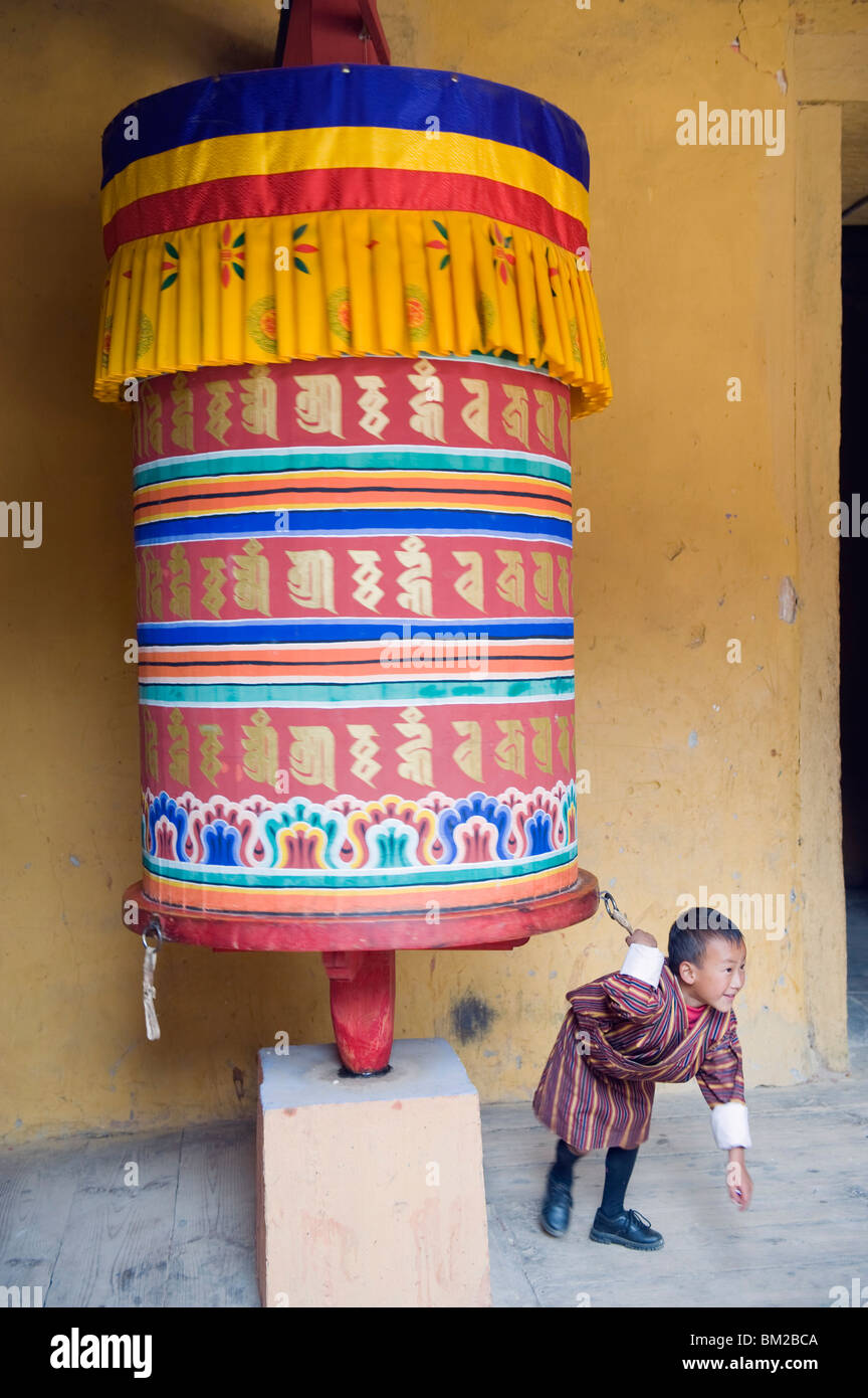 Ragazzo giovane tirando una ruota di preghiera, Jakar Dzong, Castello di White Bird, Jakar, Bumthang, Chokor Valley, Bhutan Foto Stock