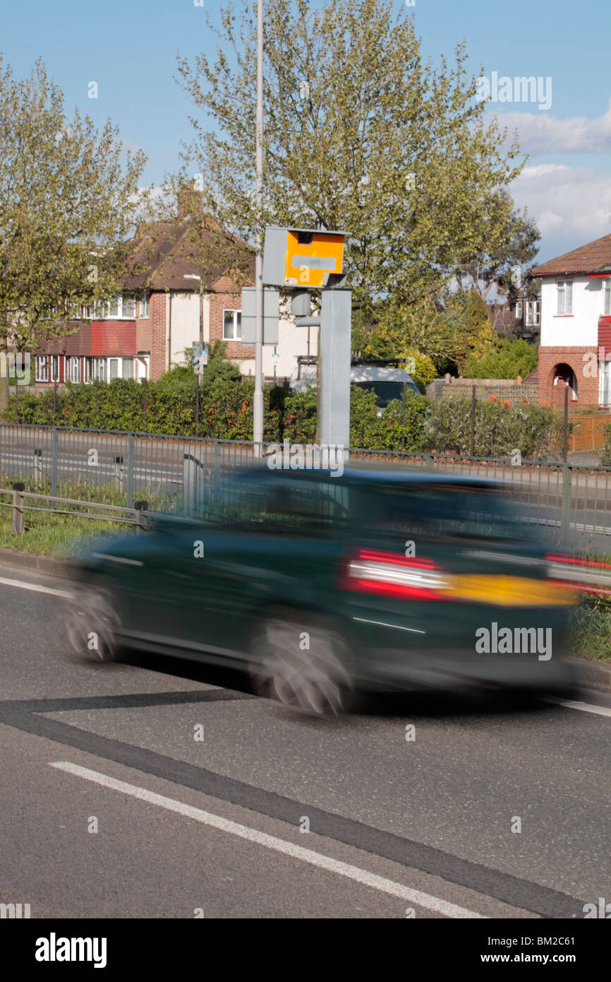 Un verde scuro auto velocizzando il passato una velocità Gatso fotocamera sulla A316 Grande Chertsey Road, Hounslow, Regno Unito. Vedi descrizione Foto Stock
