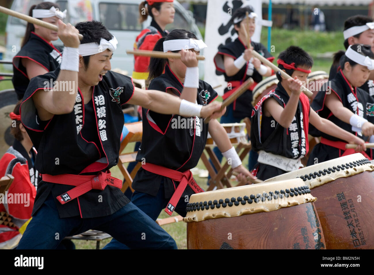 Energico gruppo di percussionisti giapponesi battendo i tamburi taiko durante una performance all'aperto, Giappone Foto Stock