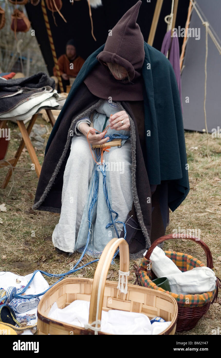 Donna in abiti medievali si intreccia nastri di lana. Viking fiera a Ale Viking Village. Svezia Foto Stock