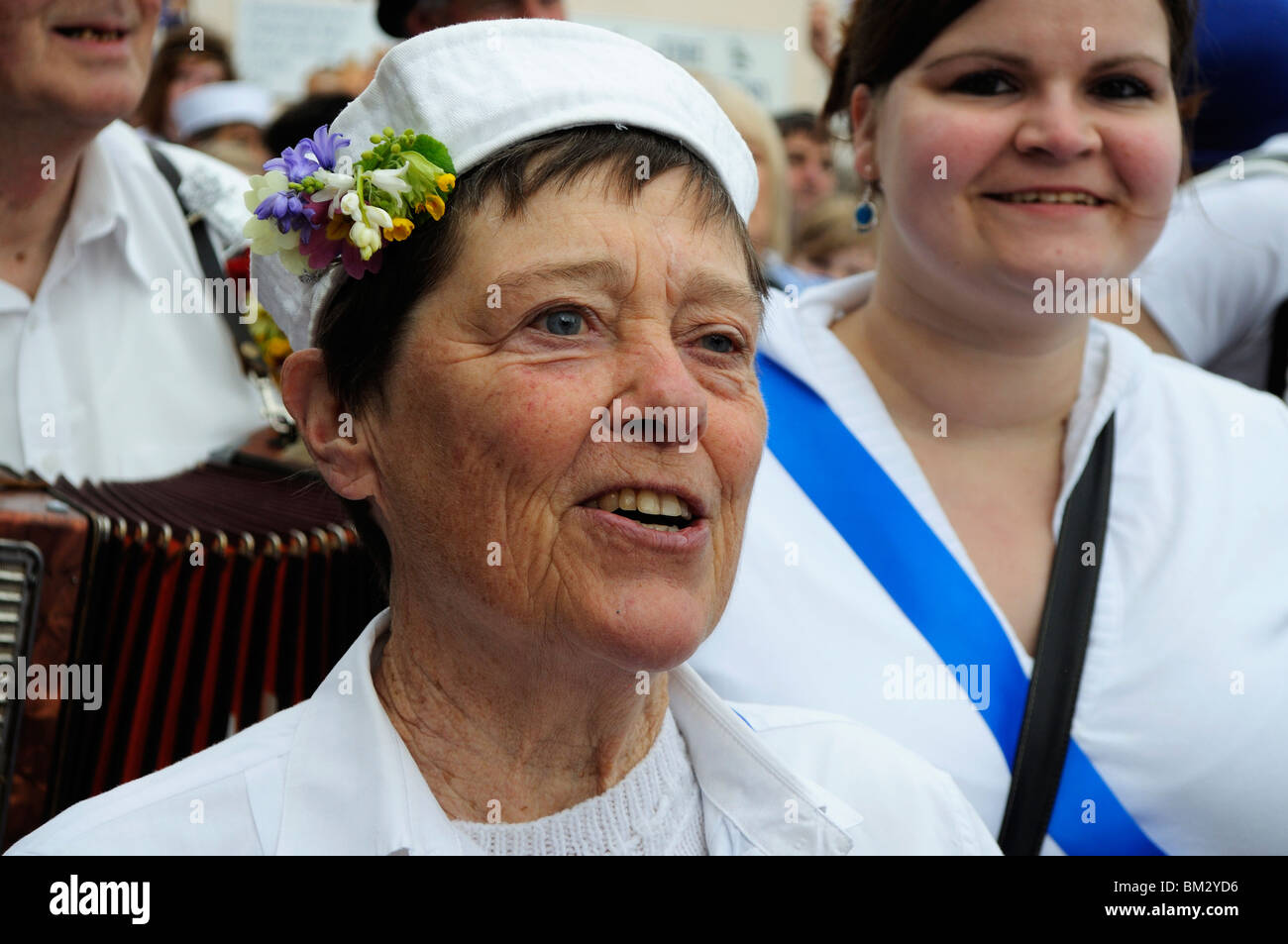 Una donna matura cantando su obby oss giorno a Padstow, Cornwall, Regno Unito Foto Stock