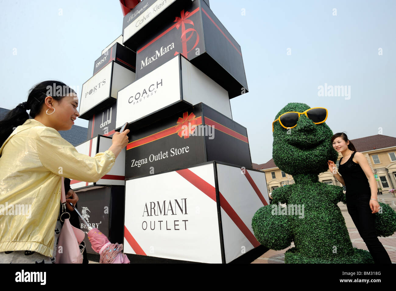 Signore cinese di scattare foto accanto a marchi di lusso bill tavole a Pechino Scitech Premium Outlet Mall di Beijing in Cina. 2010 Foto Stock