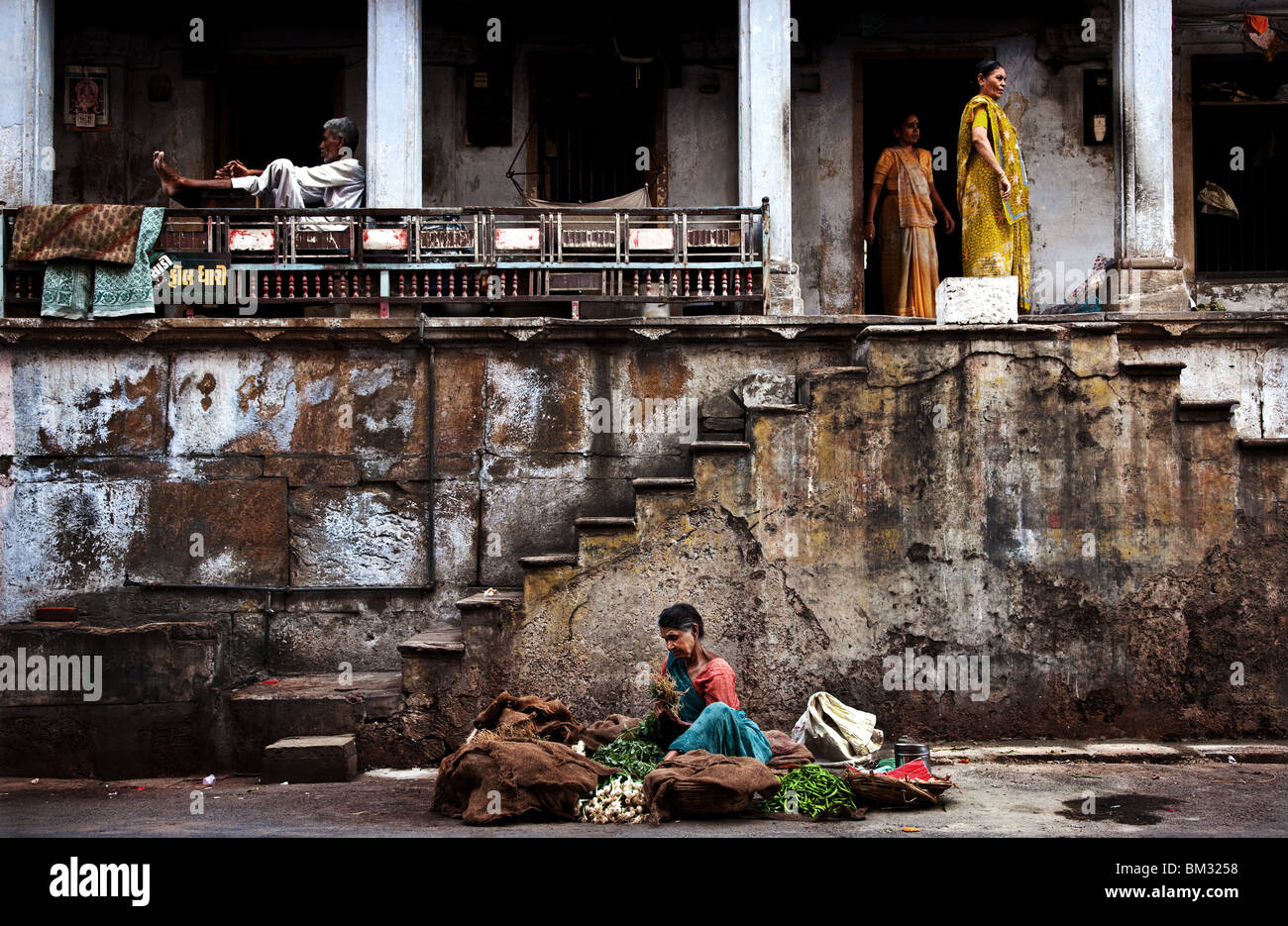L'INDIA, 12 maggio 2010: un venditore vegetali si siede sulla strada al di fuori di una vecchia casa in Ahmedabad,Gujurat,l'India. Foto Stock