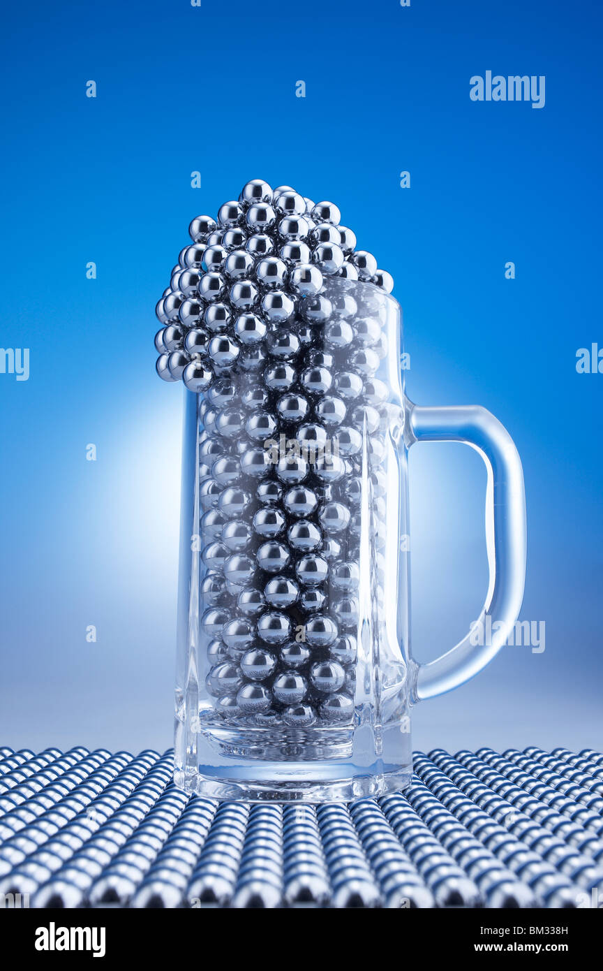 La birra di vetro riempita con sfere di Pachinko, computer grafica, sfondo blu Foto Stock
