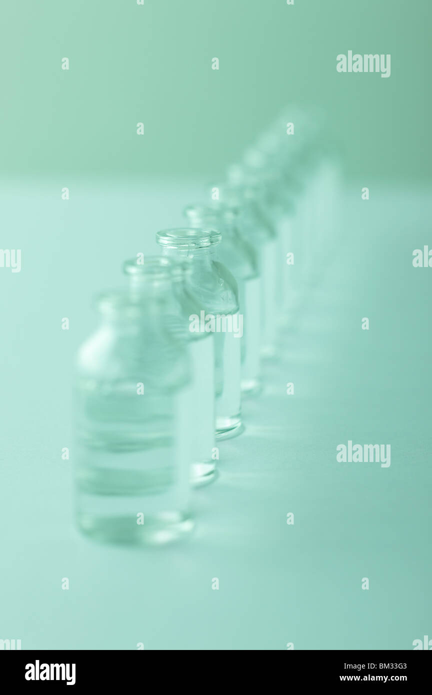 Fila di bottiglie di vetro con acqua, sfondo verde, soft focus Foto Stock