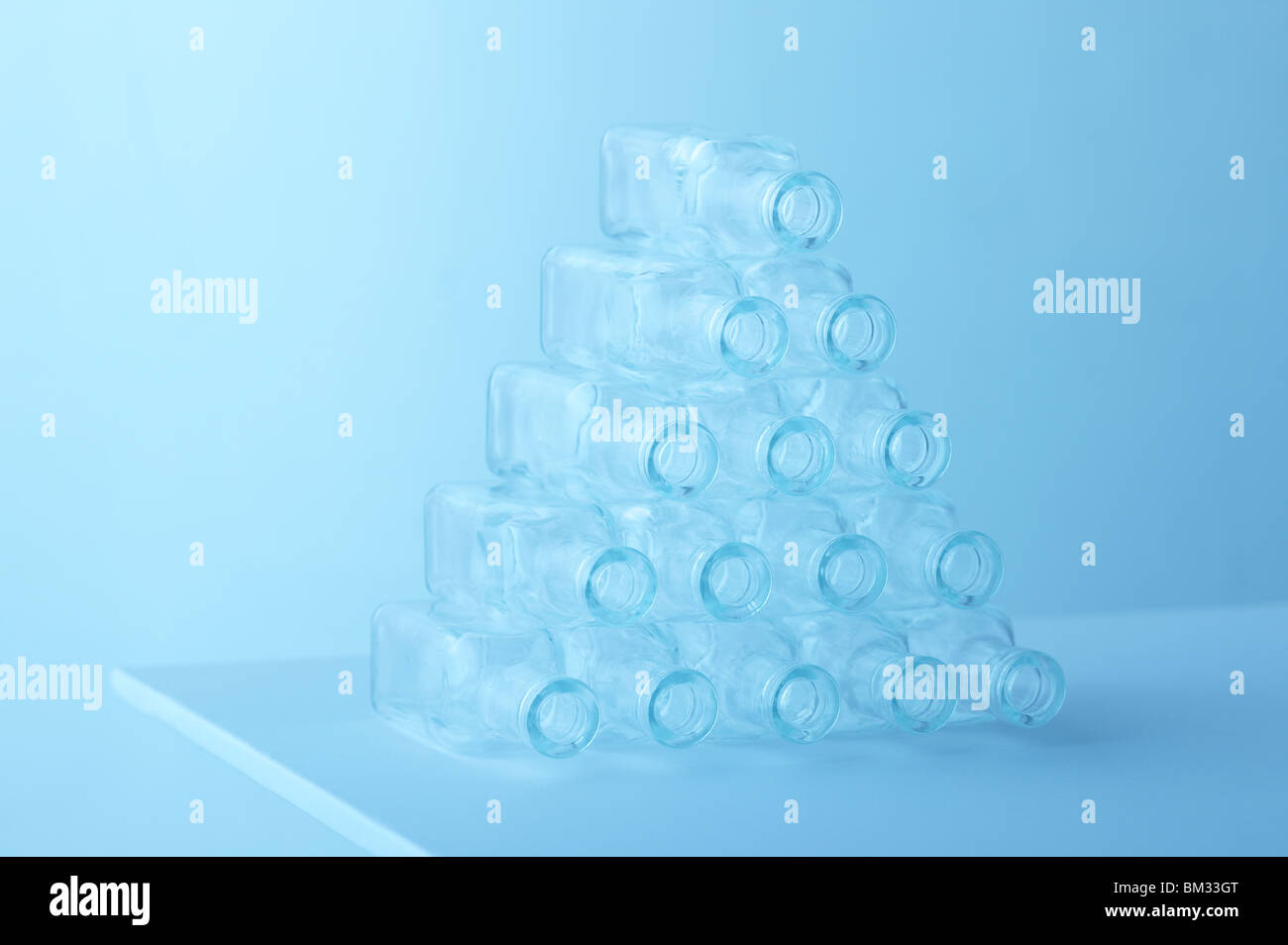 Svuotare le bottiglie di vetro disperse fino a piramide, sfondo blu, soft focus Foto Stock