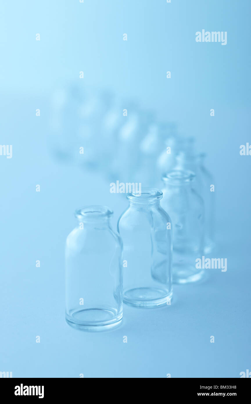 Fila di svuotare le bottiglie di vetro, sfondo blu, soft focus Foto Stock