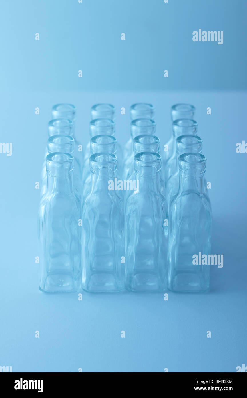 Righe di svuotare le bottiglie di vetro su tavola, sfondo blu, soft focus Foto Stock