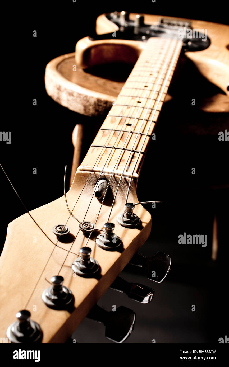 Chitarra elettrica sulla sedia in legno - prese in condizioni di scarsa illuminazione tasto Foto Stock