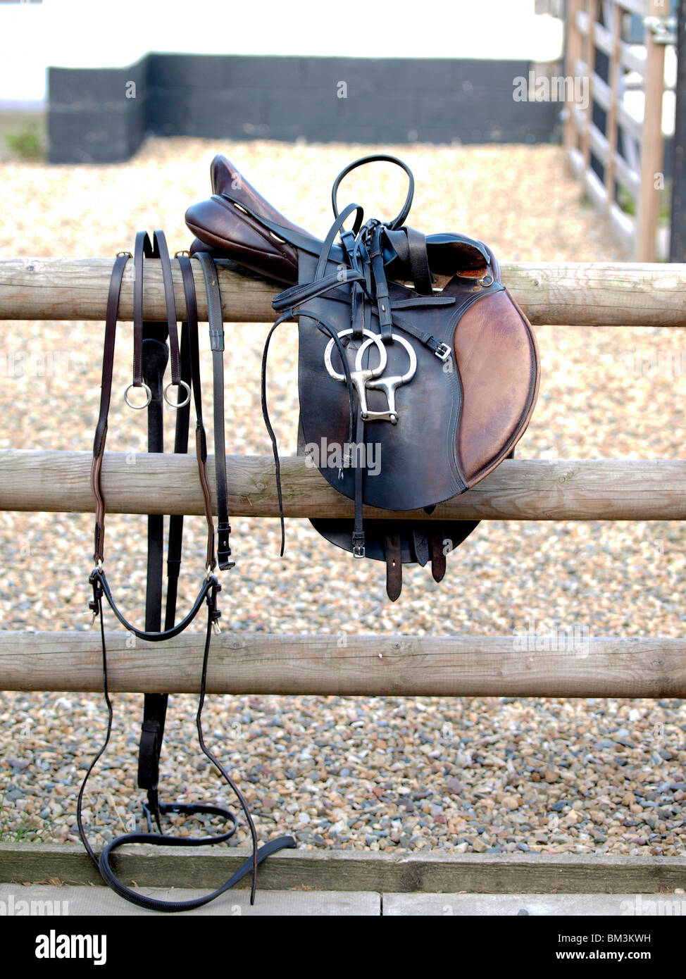 Una sella e briglia con redini appesi in una recinzione di legno Foto Stock