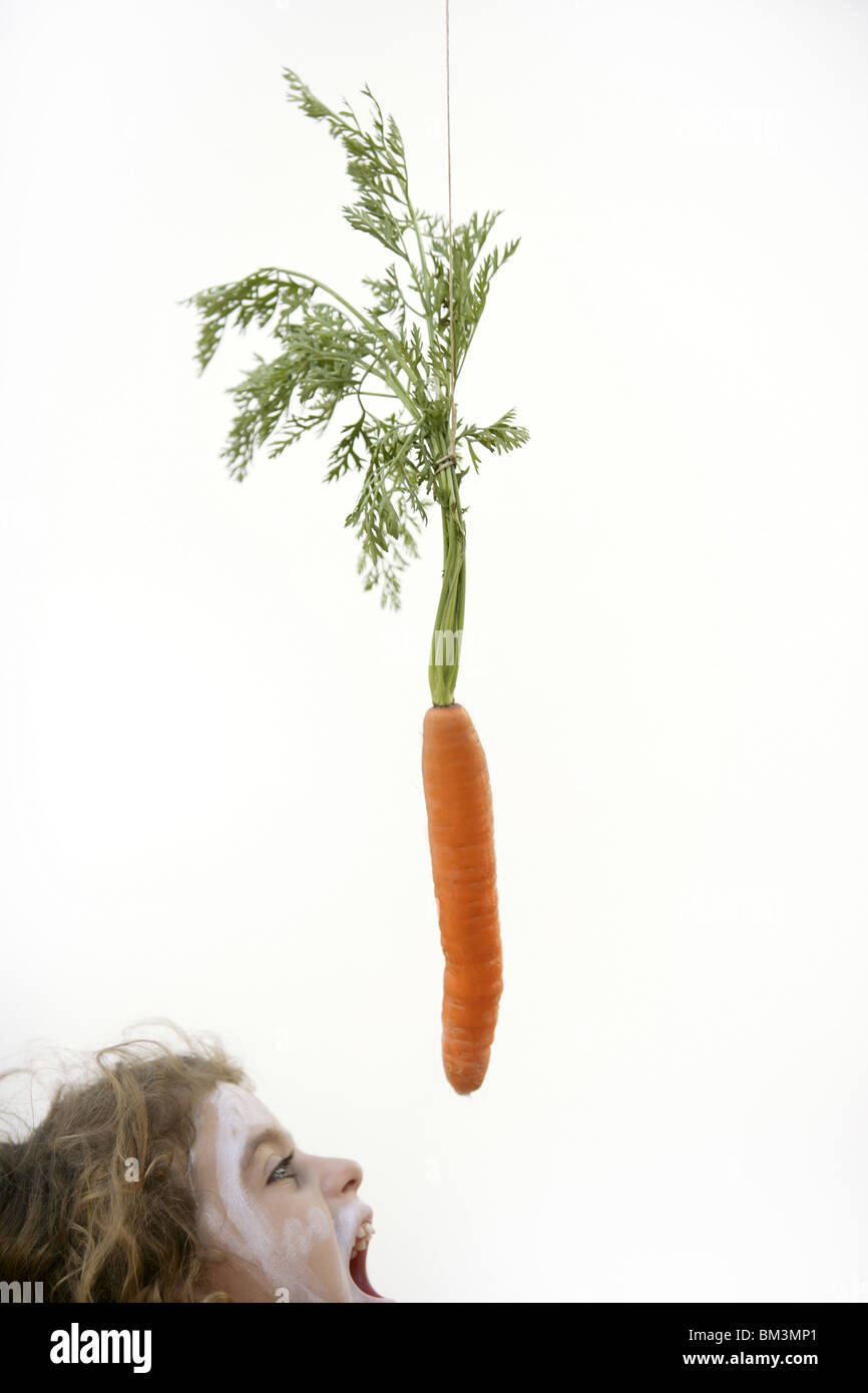 Ragazza saltando a mangiare la carota trappola di coniglio con bocca aperta Foto Stock