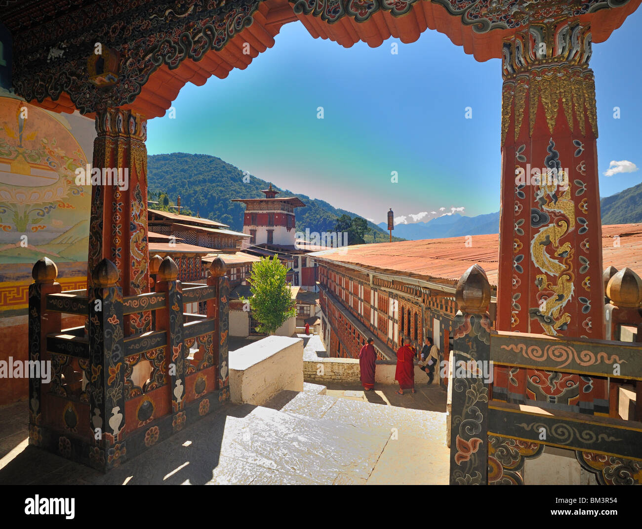 Vista dal tempio oltre il cortile con i monaci e uomo in abito nazionale, Trongsa Dzong, Bhutan. Foto Stock