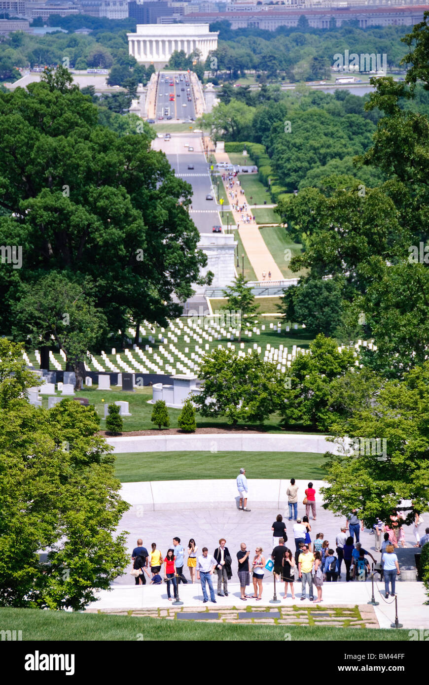 John F Kennedy Gravesite Eternal Flame Arlington Virginia // ARLINGTON, Virginia - i visitatori si riuniscono presso la tomba del presidente John F. Kennedy nel cimitero nazionale di Arlington, segnato dalla fiamma eterna. La vista da Arlington House (il Robert E. Lee Memorial) cattura l'Arlington Memorial Bridge che attraversa il fiume Potomac con il Lincoln Memorial visibile sulla riva opposta di Washington DC. Foto Stock