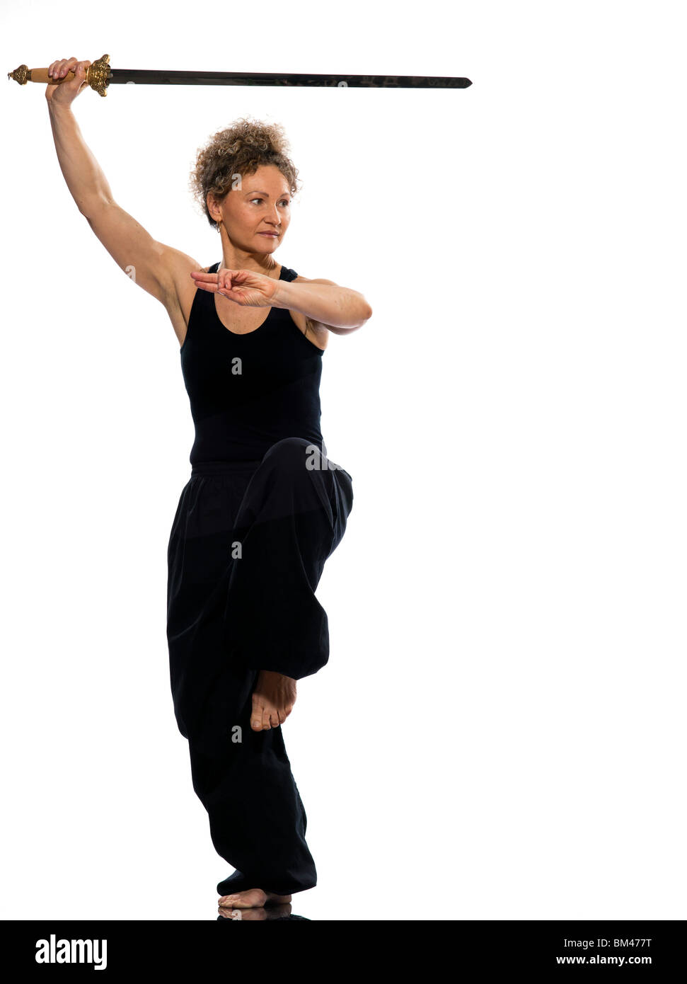 Donna matura praticing tai chi chuan con la spada in studio isolato su sfondo bianco Foto Stock