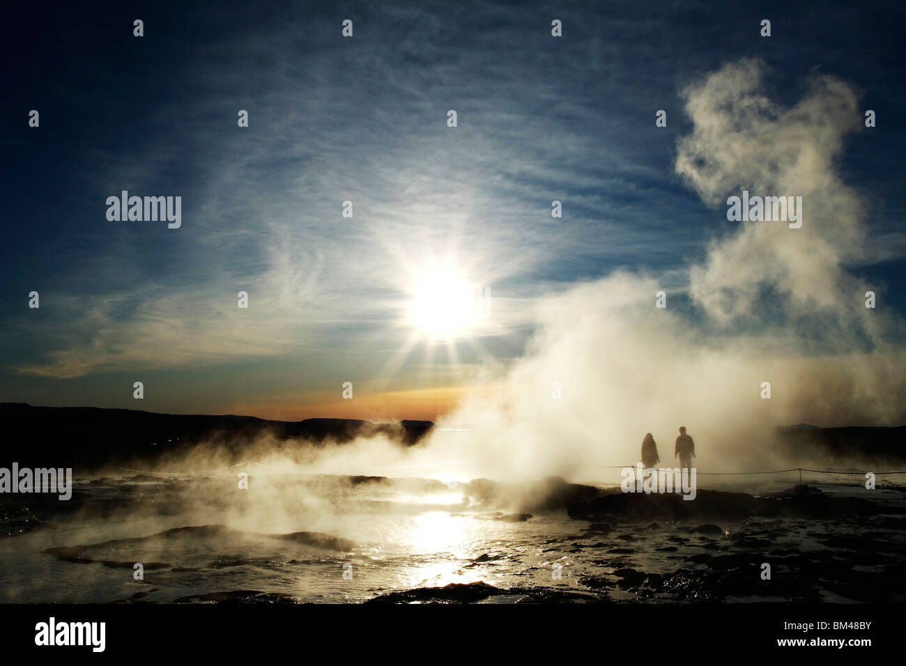 I turisti si stagliano in vapore dalla Strokkur geyser a Haukadalur valley, un attivo area geotermica di Islanda Foto Stock