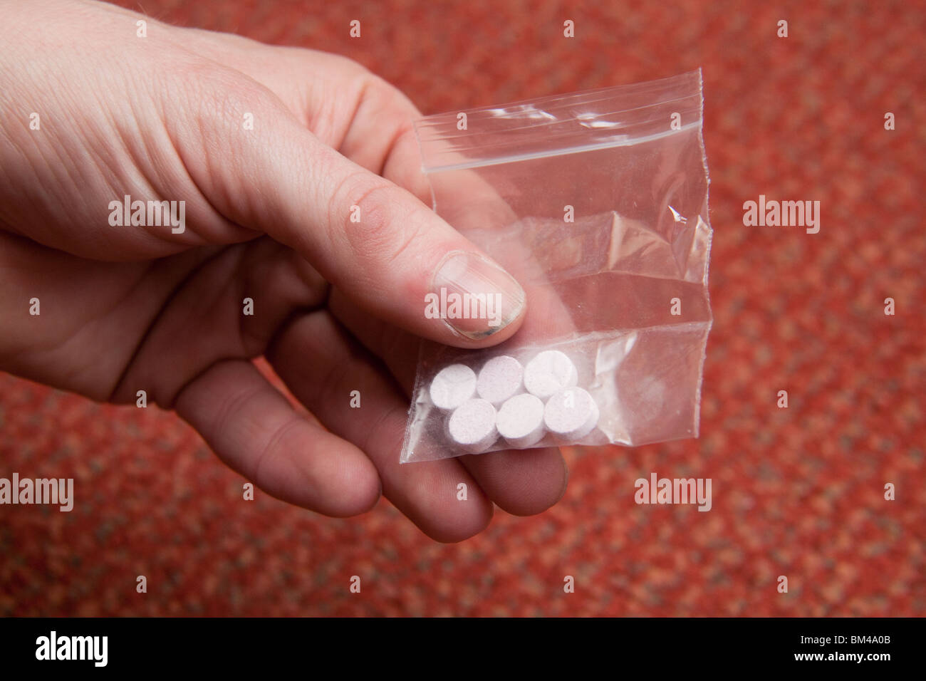 Borsa di sei di pillole di ecstasy in un mans mano. Foto Stock