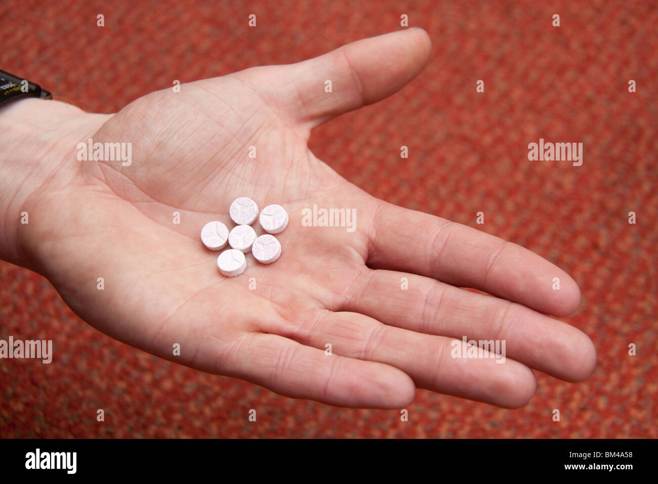 Pillole di ecstasy in un mans mano. Foto Stock