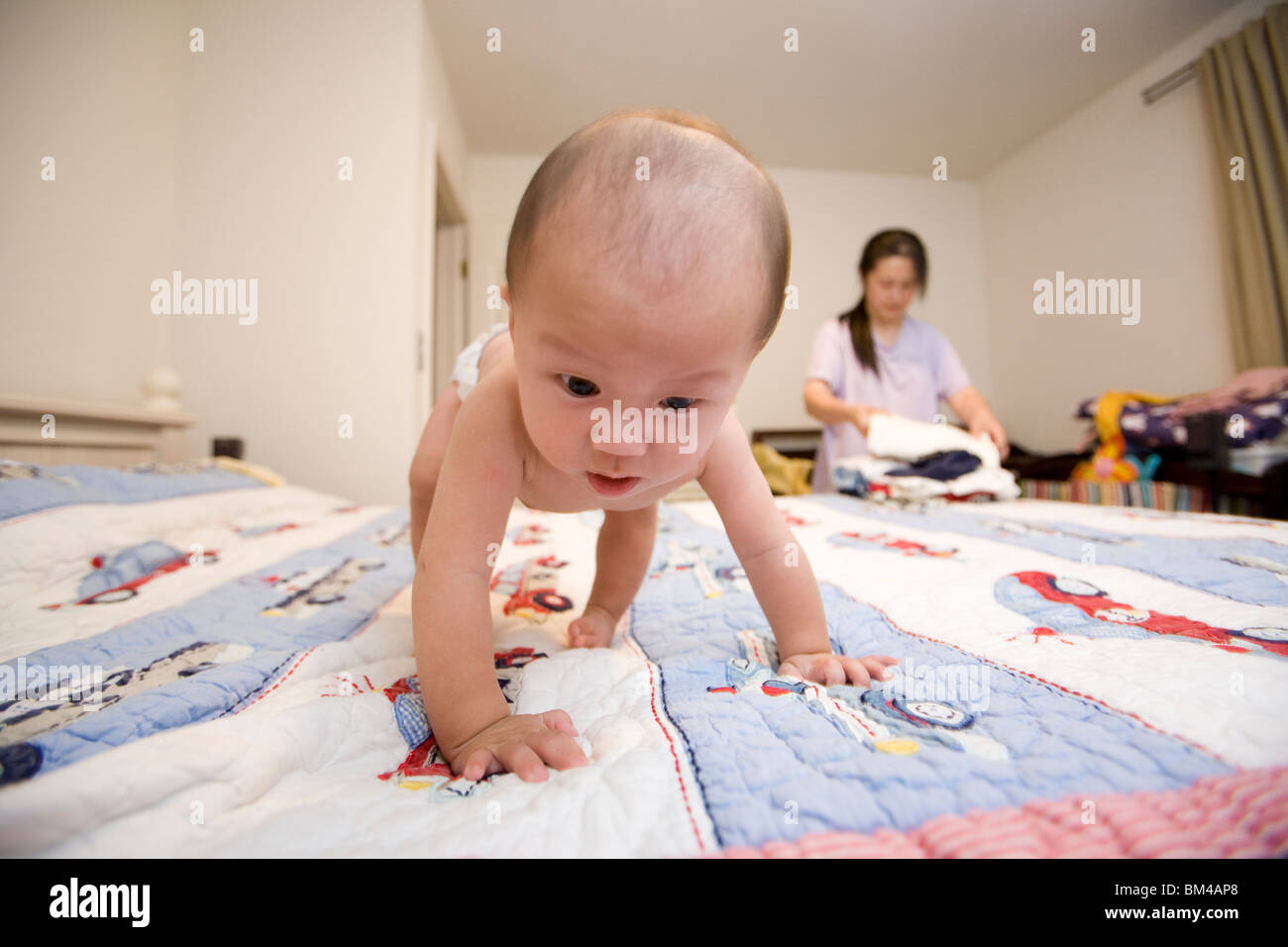 Asian baby boy strisciando sul letto Foto Stock