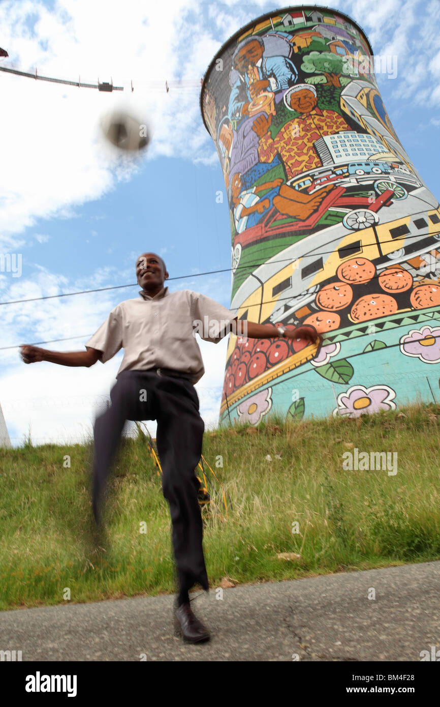 Un uomo gioca con un pallone da calcio in Soweto appena fuori di  Johannesburg, Sud Africa di fronte al dipinto di pile di fumo Foto stock -  Alamy
