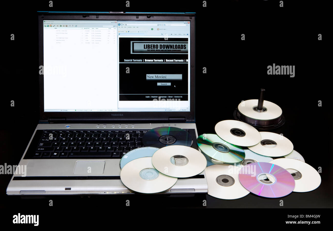 Download illegali e sito web sito bittorrent su un computer accanto a un mucchio di copiare DVD. Foto Stock